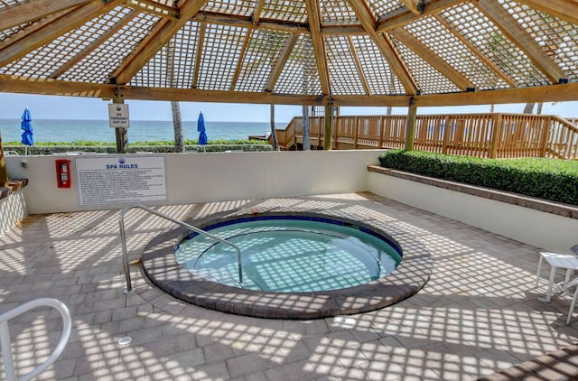 view of swimming pool with a gazebo, a water view, and a hot tub