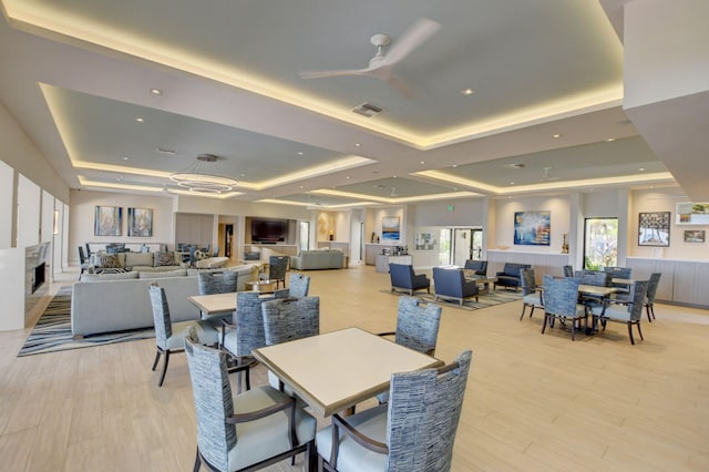 dining room featuring a tray ceiling, light hardwood / wood-style flooring, ceiling fan, and coffered ceiling