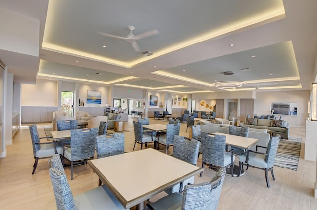 dining space with ceiling fan and a tray ceiling