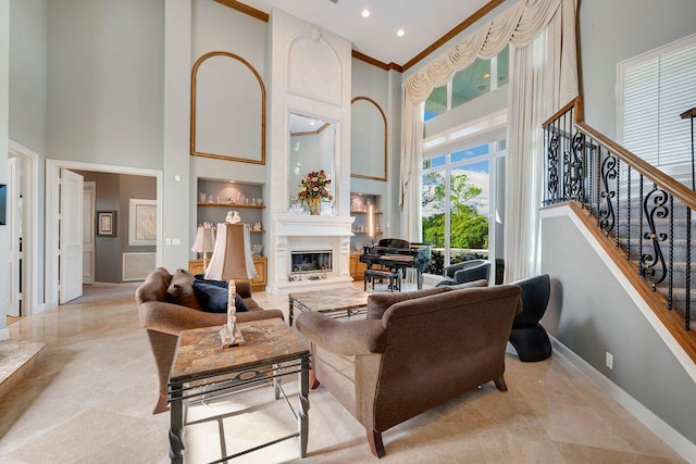 living room featuring built in shelves, a large fireplace, crown molding, and a high ceiling