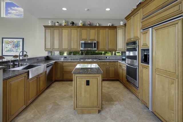 kitchen with sink, a center island, dark stone counters, kitchen peninsula, and stainless steel appliances