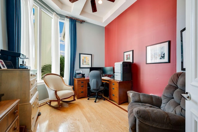 office space with a raised ceiling, ceiling fan, and light hardwood / wood-style flooring