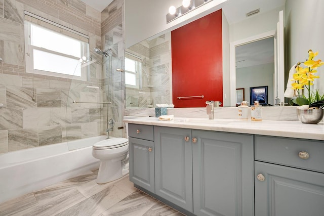 full bathroom featuring tiled shower / bath, vanity, and toilet