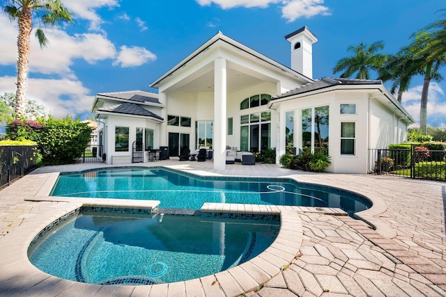 back of property featuring a swimming pool with hot tub and a patio area