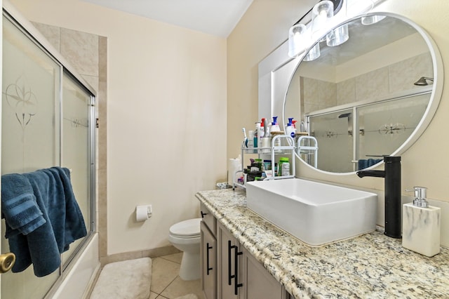 full bathroom featuring vanity, combined bath / shower with glass door, toilet, and tile patterned flooring