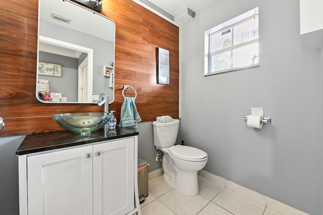 bathroom with toilet, vanity, tile patterned floors, and wooden walls