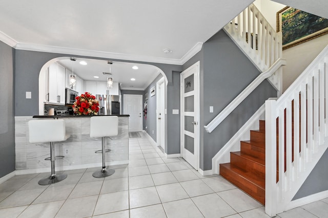 kitchen featuring white cabinets, appliances with stainless steel finishes, a breakfast bar, ornamental molding, and decorative light fixtures