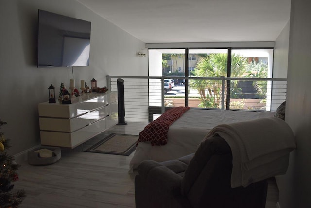 bedroom with a wall of windows and hardwood / wood-style floors