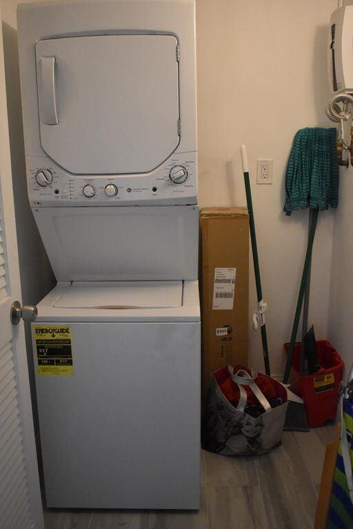 laundry area featuring wood-type flooring and stacked washing maching and dryer