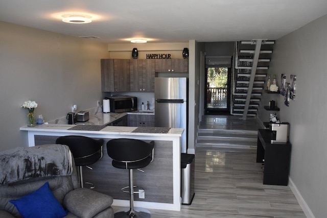 kitchen featuring stainless steel appliances, kitchen peninsula, and a breakfast bar area