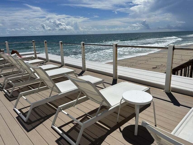 wooden terrace with a water view and a view of the beach