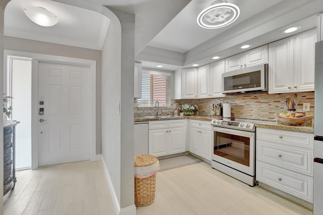 kitchen with white cabinetry, sink, light hardwood / wood-style floors, appliances with stainless steel finishes, and backsplash