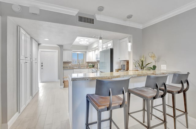 kitchen with white cabinetry, backsplash, light stone countertops, and kitchen peninsula