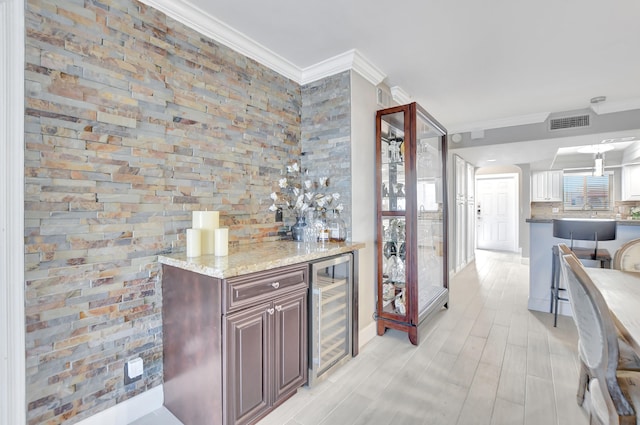 kitchen with crown molding, light stone countertops, and wine cooler