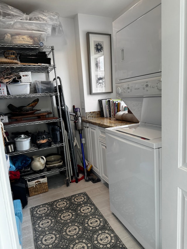 laundry area featuring cabinets and stacked washing maching and dryer