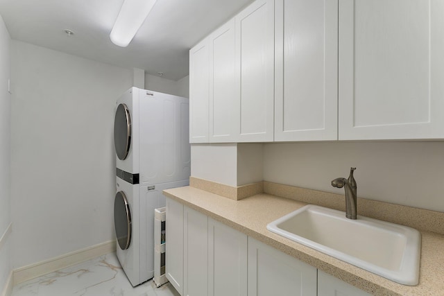 washroom with cabinets, stacked washer / drying machine, and sink