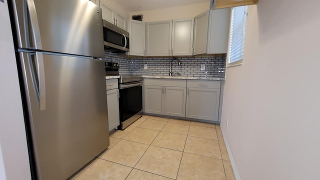 kitchen with sink, gray cabinets, tasteful backsplash, light tile patterned flooring, and stainless steel appliances