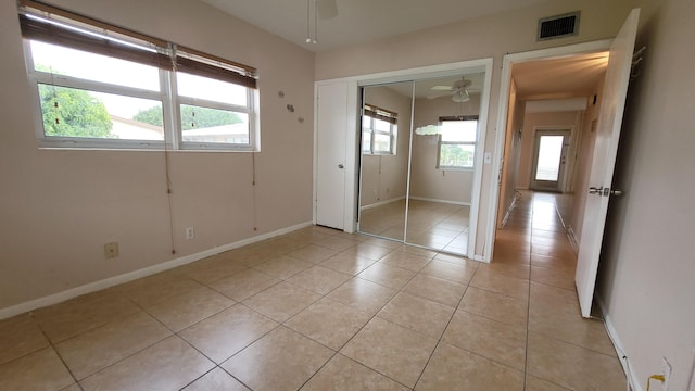 unfurnished bedroom with ceiling fan, light tile patterned floors, and a closet