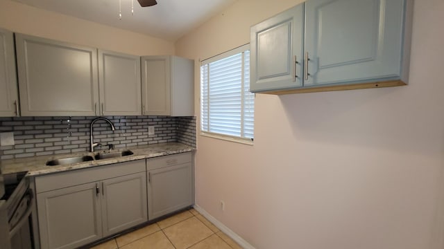 kitchen featuring tasteful backsplash, light stone counters, gray cabinetry, sink, and light tile patterned flooring