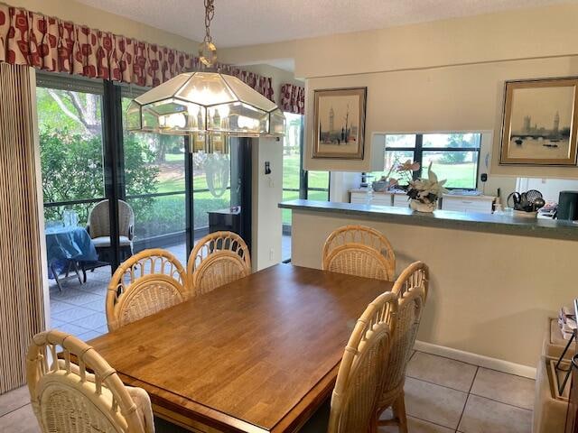 tiled dining room with a notable chandelier, a textured ceiling, and a healthy amount of sunlight