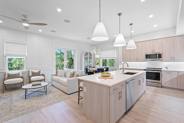 kitchen with a healthy amount of sunlight, sink, stainless steel appliances, and decorative light fixtures