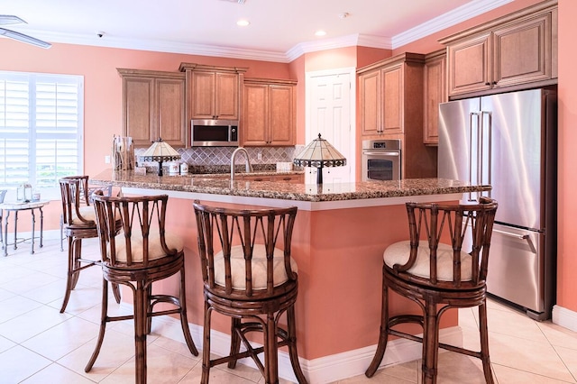 kitchen featuring a breakfast bar, appliances with stainless steel finishes, a spacious island, light tile patterned flooring, and decorative backsplash