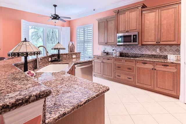 kitchen featuring appliances with stainless steel finishes, sink, backsplash, ceiling fan, and crown molding