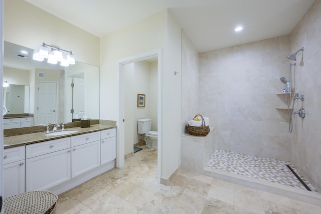 bathroom featuring a tile shower, vanity, and toilet