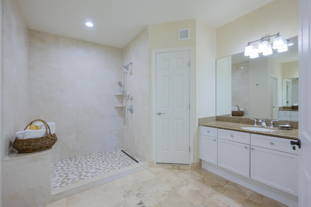 bathroom with a tile shower and vanity