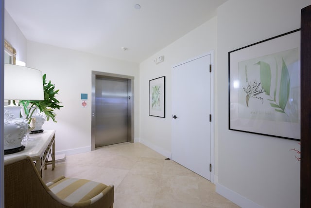 hallway with elevator and light tile patterned floors