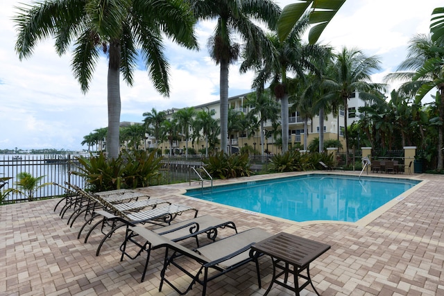 view of swimming pool featuring a water view and a patio