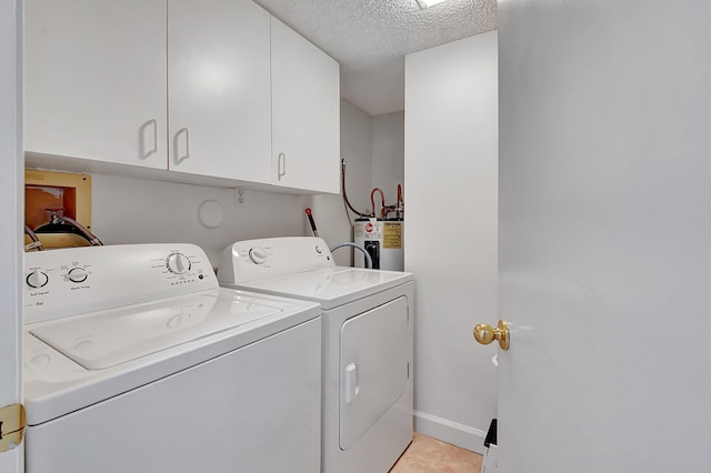 laundry area featuring light tile patterned floors, washing machine and dryer, electric water heater, cabinets, and a textured ceiling