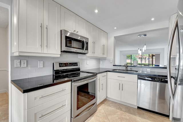 kitchen with sink, tasteful backsplash, pendant lighting, stainless steel appliances, and white cabinets