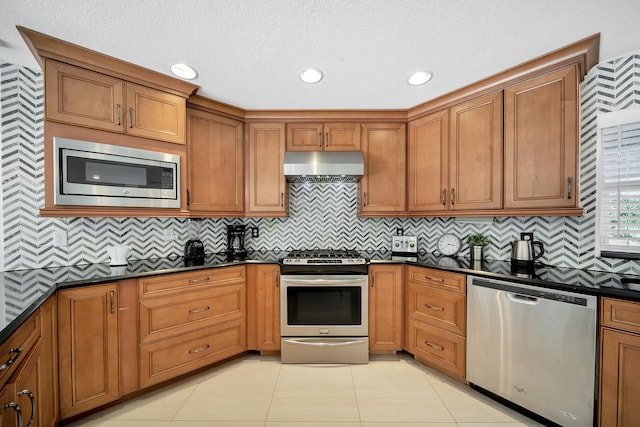 kitchen featuring dark stone countertops, a textured ceiling, backsplash, and stainless steel appliances