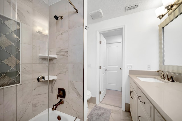 full bathroom with tiled shower / bath, toilet, a textured ceiling, and vanity