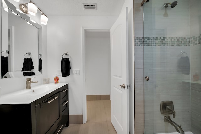 bathroom with tiled shower, vanity, tile patterned floors, and a textured ceiling