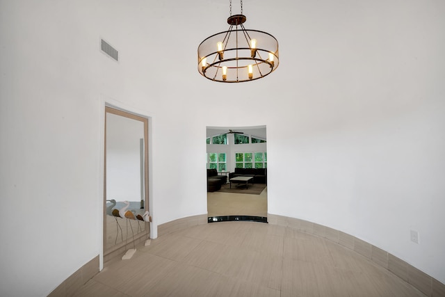 hall with a high ceiling, light tile patterned floors, and a chandelier