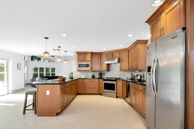 kitchen featuring a breakfast bar area, decorative light fixtures, appliances with stainless steel finishes, tasteful backsplash, and kitchen peninsula