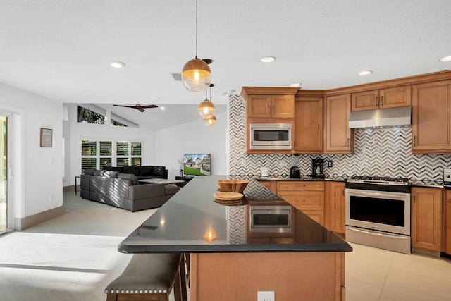 kitchen with pendant lighting, a kitchen island, backsplash, and appliances with stainless steel finishes