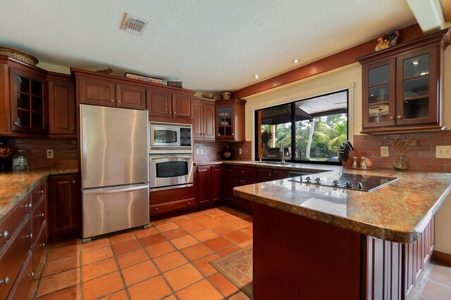 kitchen with sink, appliances with stainless steel finishes, tasteful backsplash, light tile patterned flooring, and kitchen peninsula