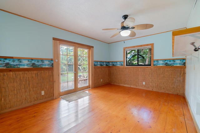 empty room featuring french doors, light hardwood / wood-style flooring, ceiling fan, and ornamental molding