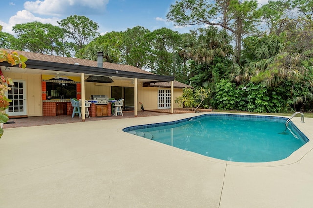 view of pool featuring french doors, area for grilling, a patio area, an outdoor bar, and a grill