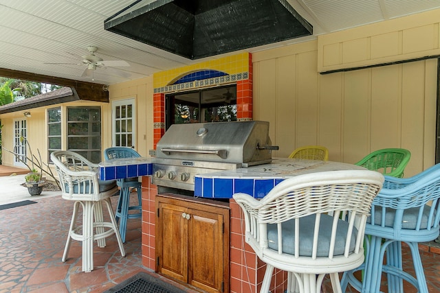 view of patio featuring a bar, an outdoor kitchen, grilling area, and ceiling fan