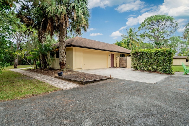 exterior space with aphalt driveway, an attached garage, and a front lawn