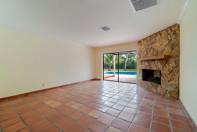 unfurnished living room with a fireplace, a textured ceiling, tile patterned flooring, and crown molding