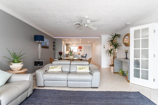 living room featuring light tile patterned flooring, crown molding, ceiling fan, and a textured ceiling