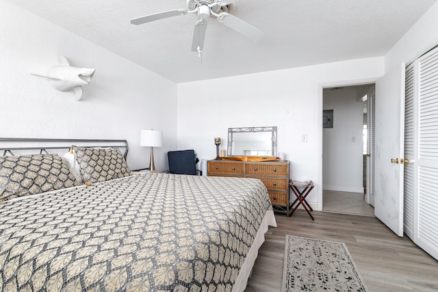 bedroom featuring a textured ceiling, a closet, ceiling fan, and light wood-type flooring