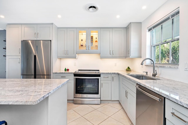 kitchen featuring light stone counters, appliances with stainless steel finishes, sink, and gray cabinetry