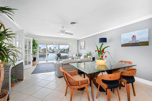 dining space with a water view, ornamental molding, a textured ceiling, and light tile patterned floors