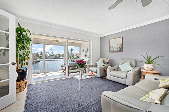 living room featuring light tile patterned floors, crown molding, ceiling fan, a water view, and a textured ceiling